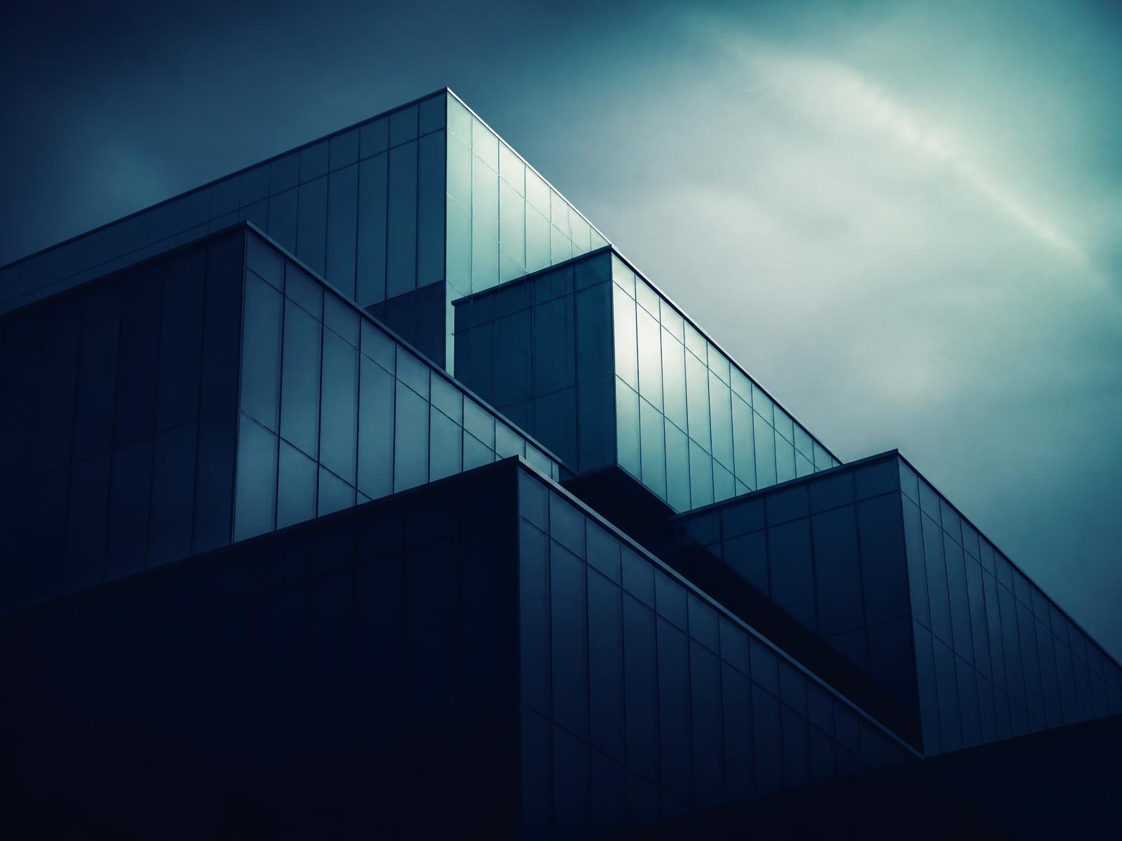 Layered modern glass corporate facade emerging from shadow into light